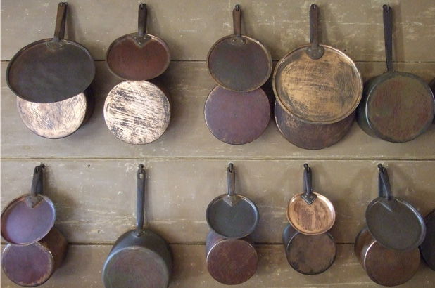 Batterie de cuisine, rows of cooking pans and lids hung on the wall.