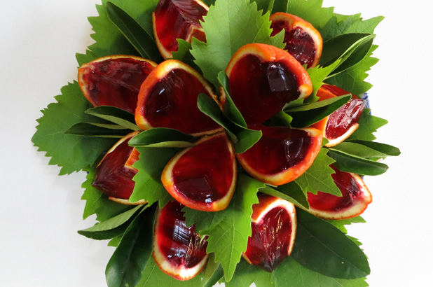 Jelly filled oranges cut into wedges and decorated with grape leaves.