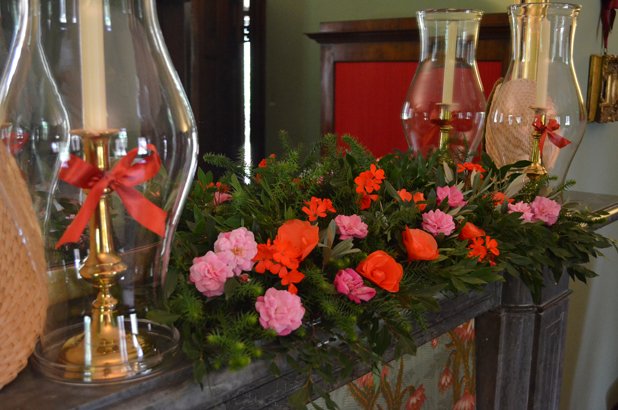 An arrangement of flowers, greenery and candle shades on the chimneypiece at Elizabeth Farm.