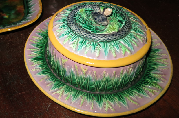 A covered serving dish decorated with a snake and leaves.