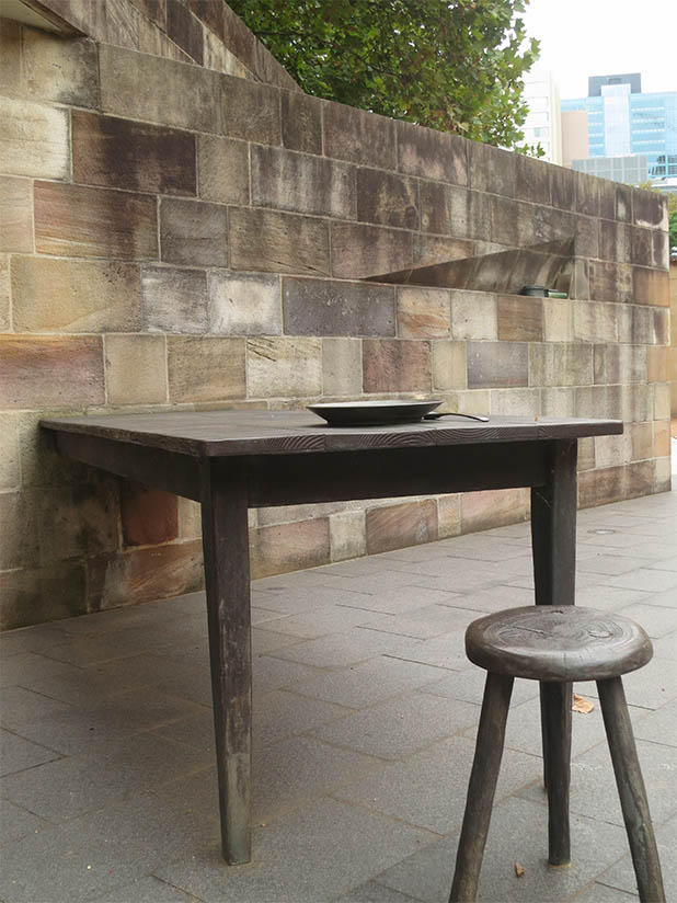 A table and stool, plate and spoon, part of the Irish Famine Memorial.