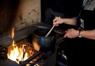 Jacqui Newling stirring a pot over the fire in the kitchen at Vaucluse House.